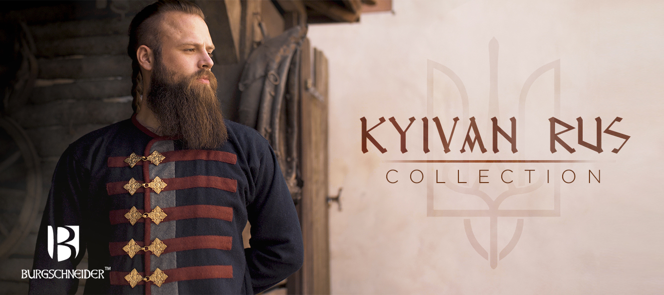 The model wears the darkblue Rus Coat Kosma with red and grey stripes and brass closures. Text on the banner says Kyivan Rus Collection.